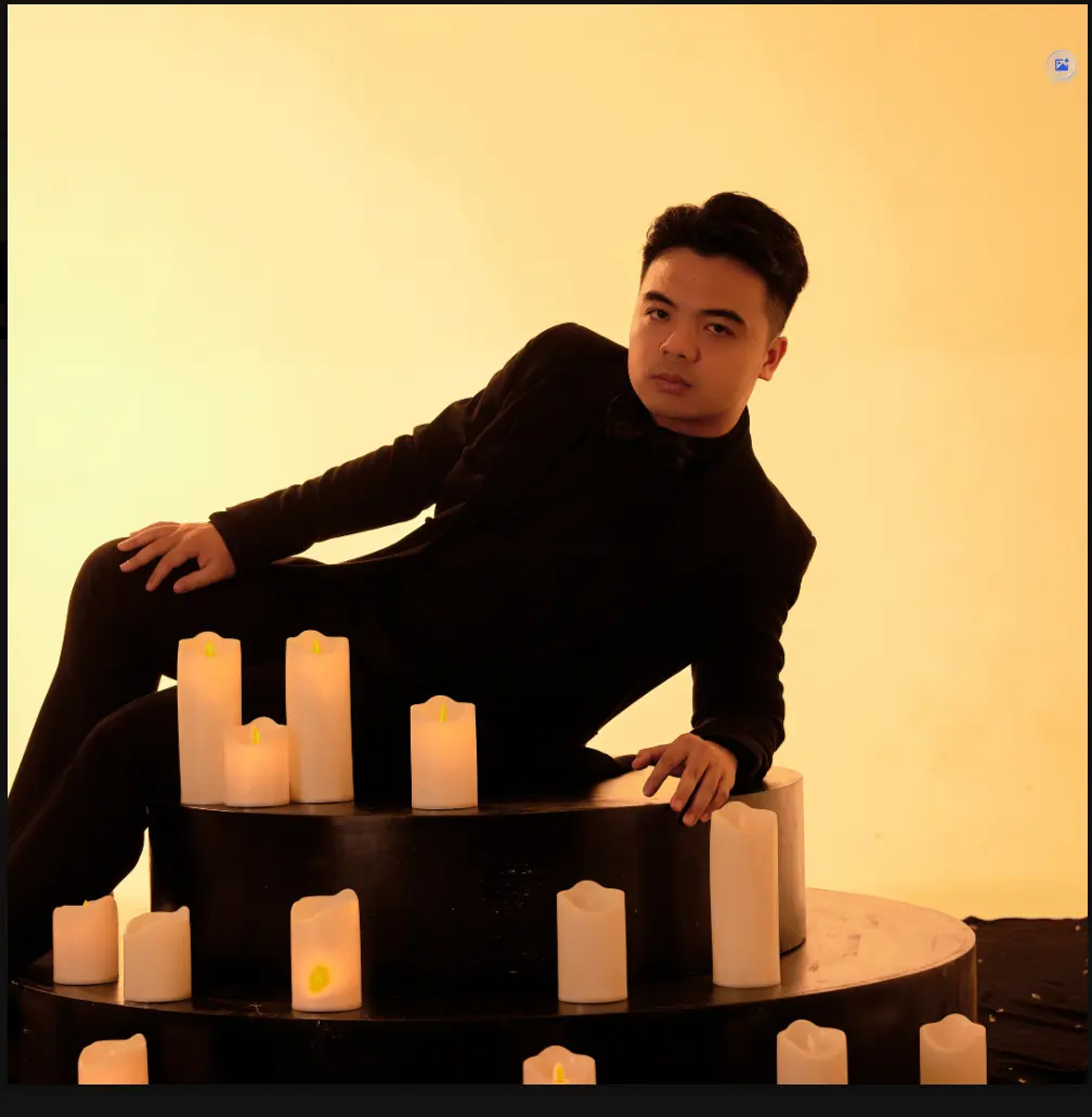 ViAM in a black suit surrounded by warm candlelight